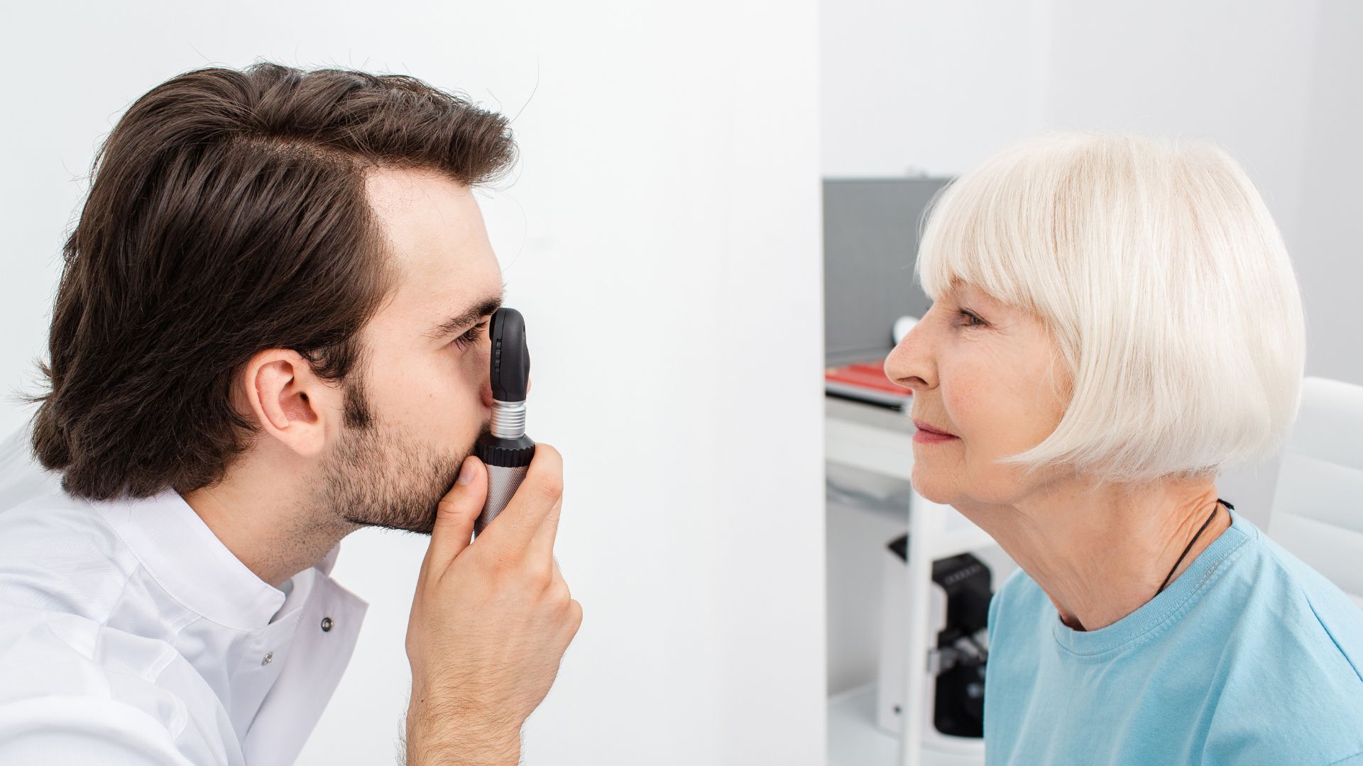 A bright and well-lit ophthalmology exam room. In the foreground, a patient sits in a comfortable chair, their eyes attentively focused on the eye doctor, who stands before them wielding an ophthalmoscope. The doctor's gaze is intense, examining the patient's eyes for signs of cataracts. Subtle medical equipment, such as a slit lamp and phoropter, are visible in the middle ground, hinting at the thorough diagnostic process. The background features clean, white walls and subtle accents of warm wood, creating a calming and professional atmosphere. Soft, directional lighting casts a gentle glow, highlighting the doctor's concentration and the patient's sense of trust and care. Cataract Symptoms 04
